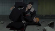 Isshin restrains Ichigo while telling him to be quiet.