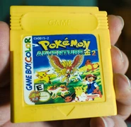A yellow cartridge with the title "Pokémon Adventure 2" on.