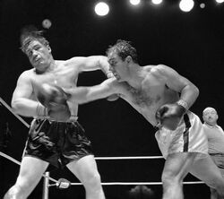 Undefeated champion Rocky Marciano inflicts heavy punch upon his opponent.