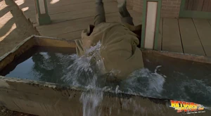 After drinking wake-up juice, Doc dunks his head in the horse trough outside the Palace Saloon.