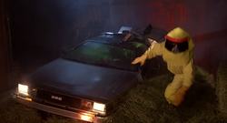 Marty, vestido con un traje anti radiación, tropieza al salir del DeLorean.