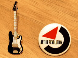 The bass guitar pin and Art in Revolution button worn on the jacket.