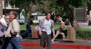 George McFly runs towards Marty, passing two boys riding orange crate scooters.
