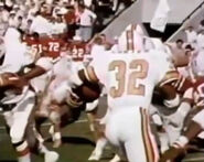 Louis Carter (No. 32) picks up speed after a second broken tackle as Jimmy DuBose (No. 35)runs left to block as Donnie Thomas (No. 51), Mel Lunsford (No. 72) and Dick Conn (No. 22) watch from the sidelines.