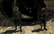 Two Shadow Company soldiers stand guard at the cave entrance to Site Hotel Bravo