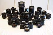 Four Canon F-1 cameras displayed alongside an assortment of FD mount lenses