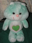 Green heart with a pink outline on a teal bear with a round pink nose. Likely protoype.
