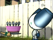 Robotboy blows out the candles on his birthday cake, but also blows it all over his friends.