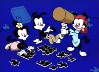 Yakko, Wakko, and Dot are working on a jigsaw puzzle. Wakko can't get his pieces to fit together, so he smashes them with his mallet.