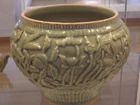 A celadon shoulder pot from the late Yuan Dynasty, displaying artwork of peaches, lotuses, peonies, willows, and palms