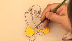 An artist is painting on a sketch for a character.