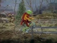 Kermit riding his bicycle.