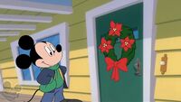 Mickey puts a wreath on his front door in "Mickey's Christmas Chaos".