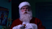 Santa wishes the viewer Merry Christmas with a cookie.
