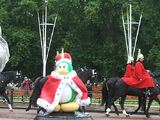 A king penguin, with men riding horses in the background