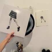 Gray holding the 7" single next to the original cover art drawings