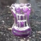 A purple Smiley with gold spray paint chipping off of it