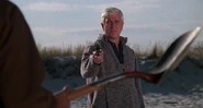 Pointing his revolver at Harry Wentworth while threatening and forcing him to bury himself in the sand.