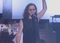 Geddy Lee giving a speech to millions of his supporters in front of the former Stairway to Heaven complex, talking about his new regime
