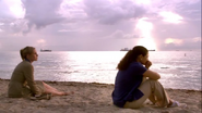 Rita sits with Yelina on the beach
