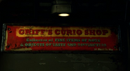A sign for Griff's Curio Shop, displaying the address, "15 Bloodox Way".