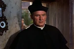 Father Murphy entering the Rathcullen Arms as he listens to one of Darby's stories about his encounter with King Brian