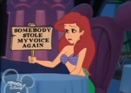 Ariel holding out a sign that says "SOMEBODY STOLE MY VOICE AGAIN"
