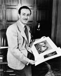 Disney posing with portraits of characters from Snow White and the Seven Dwarfs, c. 1937.