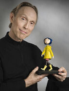 Henry Selick holding a Coraline sculpture.