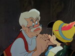 Gepetto paints a mouth and eyebrows for Pinocchio.