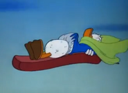 Donald Duck flies through the sky while sleeping on his mat.