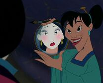 Mulán se refleja su cara maquillada en un espejo.