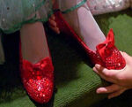 Dorothy puts the ruby slippers on Ozma's feet