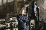 Alan Tudyk standing next to a statue of K-2SO.