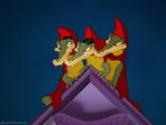 3 Alligators are wearing red capes with triangle shaped hoods on them.