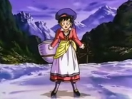 Videl wears a bright maroon dress with a green cloth wrapping around the waist, with a large hat and grey stockings