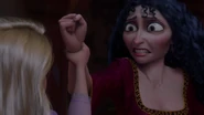 Gothel seeing Rapunzel grab her wrist as the girl stands up to her.