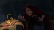 Gothel reaching over to touch the flower.