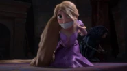 Gothel beginning to unhook Rapunzel's chains that are tied around a pillar.