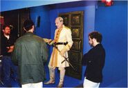 Actor John Keston dressed as Gehn, holding the prop of heek, filmed before the door to his office in Age 233. Around him are Rand Miller, Richard Vander Wende and Tim Greenberg.