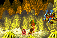 Donkey Kong about to throw a barrel at Queen B. and her Zinger minions, as seen in the game Donkey Kong Country for GBA.