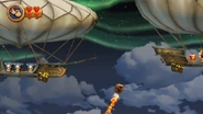 Donkey and Diddy Kong riding a Rocket Barrel through a vertical segment while avoiding airships from the Tiki Tak Tribe, as seen in the game Donkey Kong Country Returns for Wii.
