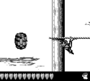 Diddy Kong moving on a horizontal rope towards an Invincibility Barrel, as seen in the game Donkey Kong Land 2 for Game Boy.