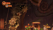 In multiplayer mode, Donkey Kong, with Diddy Kong on his back, evading some spiky boulders rolling from the background (Wii version).
