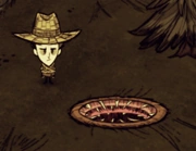 Wilson habillé d'une armure de bois et d'un chapeau de paille à côté dun Trou de Ver