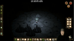 Wilson dans une cave armé d'une pioche.