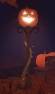 A lamp post with a pumpkin on top of it.