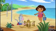 [Our story starts at the beach. Dora has a bucket and Boots is making a sand castle.]