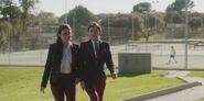 Two students walk by the tennis court at Las Encinas S01E05