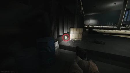 2. Caché derrière une palette de boîtes en carton à l’arrière de la salle.